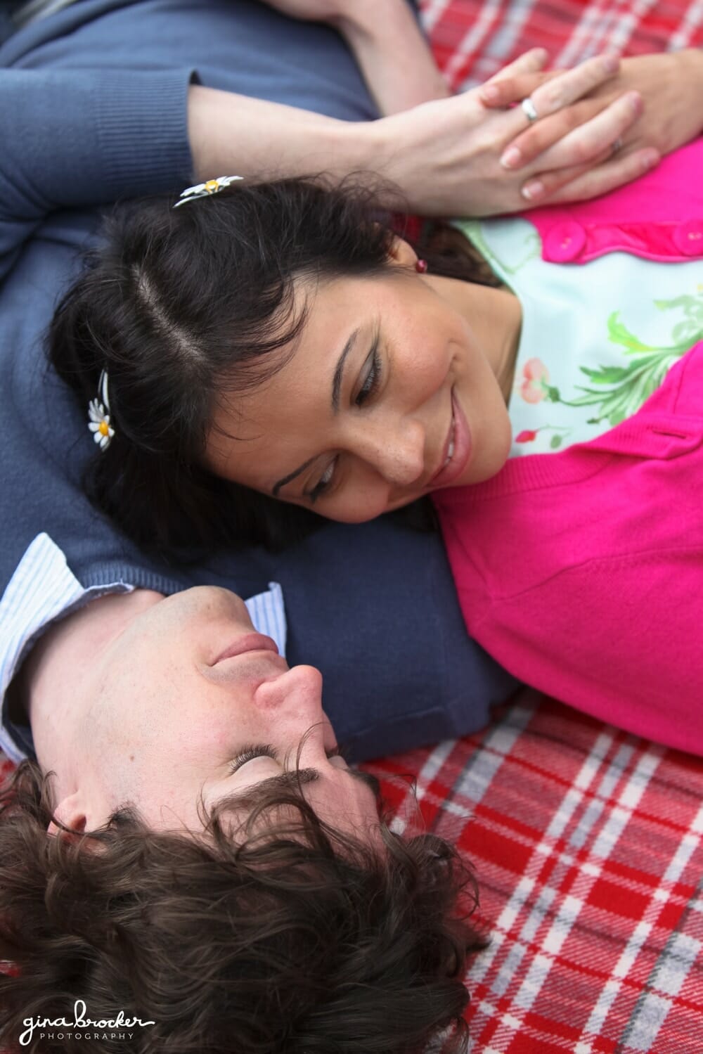 A couple lay together on a blanket during their picnic inspired engagement session in Boston, Massachusetts