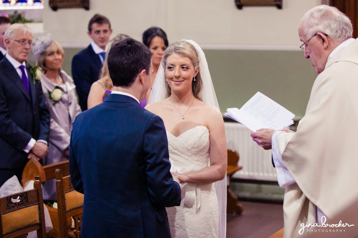 The bride smiles at her new husband while saying her wedding vows during their intimate catholic ceremony
