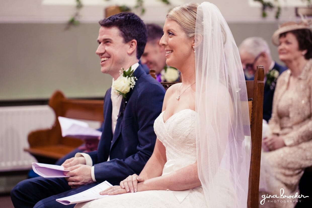 The bride and groom smile as one of their friends reads a personal message at their intimate church wedding