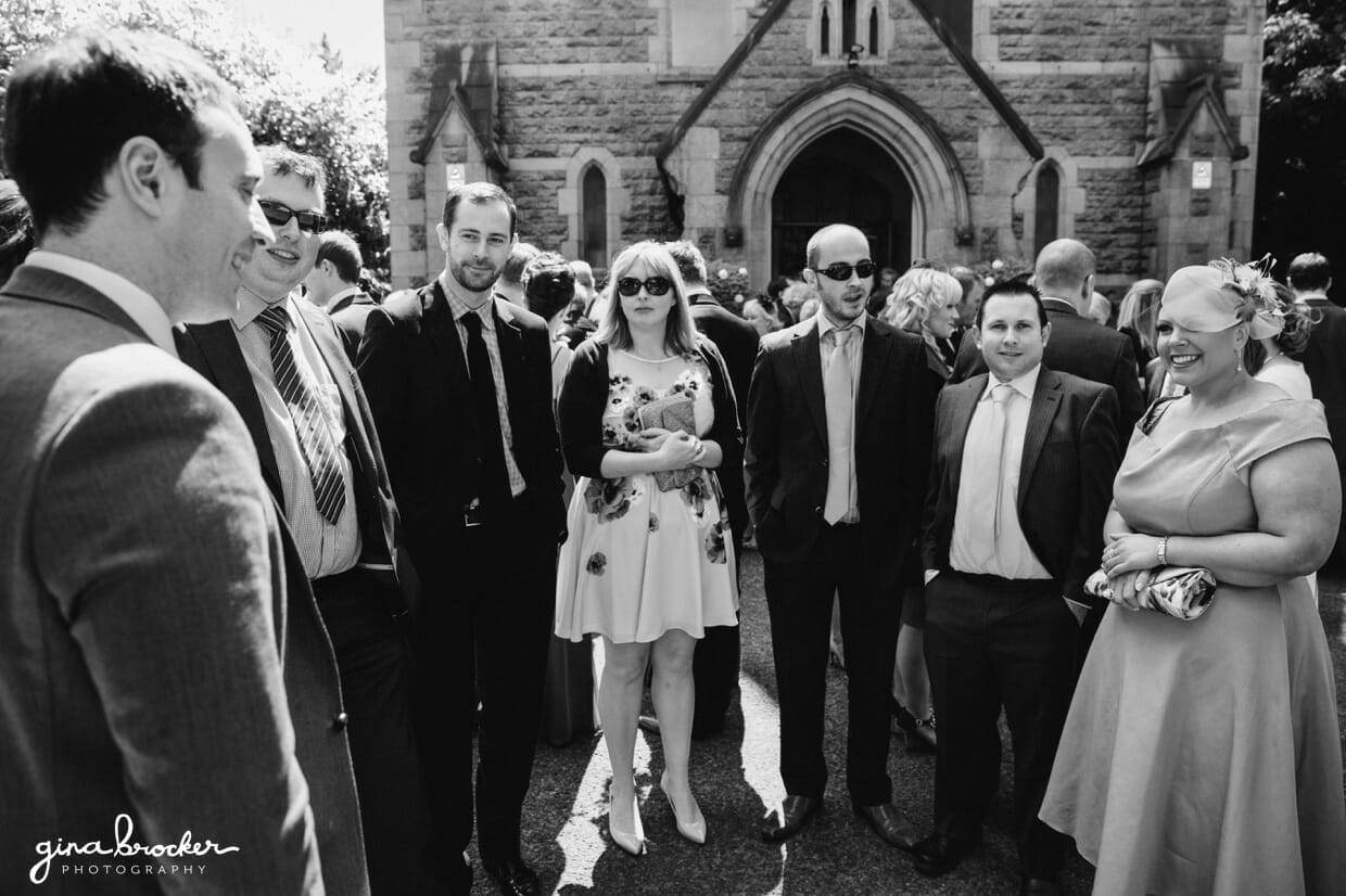 A candid photograph of the wedding guests talking after the wedding ceremony in a local church