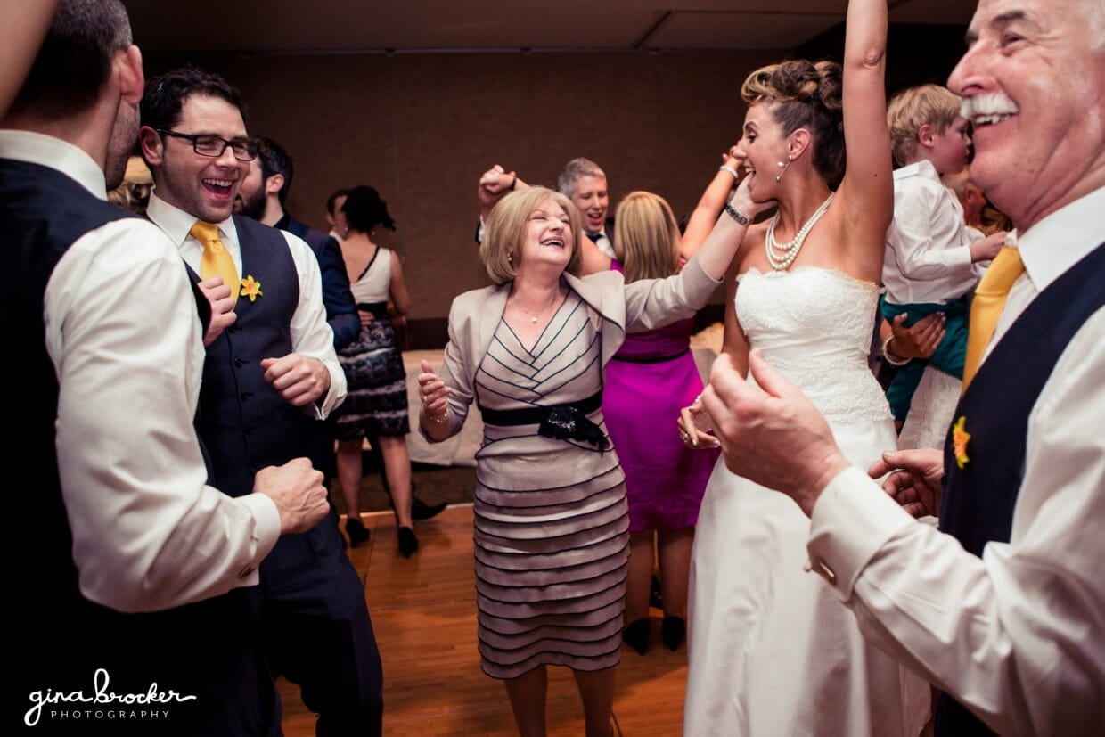 The wedding guests jump up and down while dancing at this fun wedding with retro details