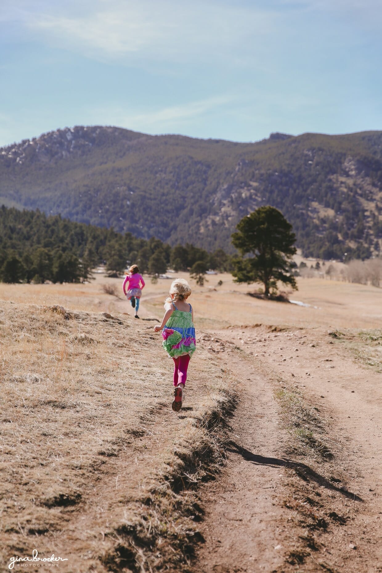 Two sisters run towards the mountains during their outdoor family photography session