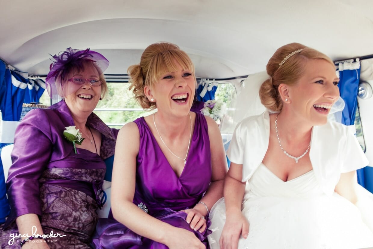A bride laughs with her mother and sister on their way to the wedding ceremony in a blue vw bus.