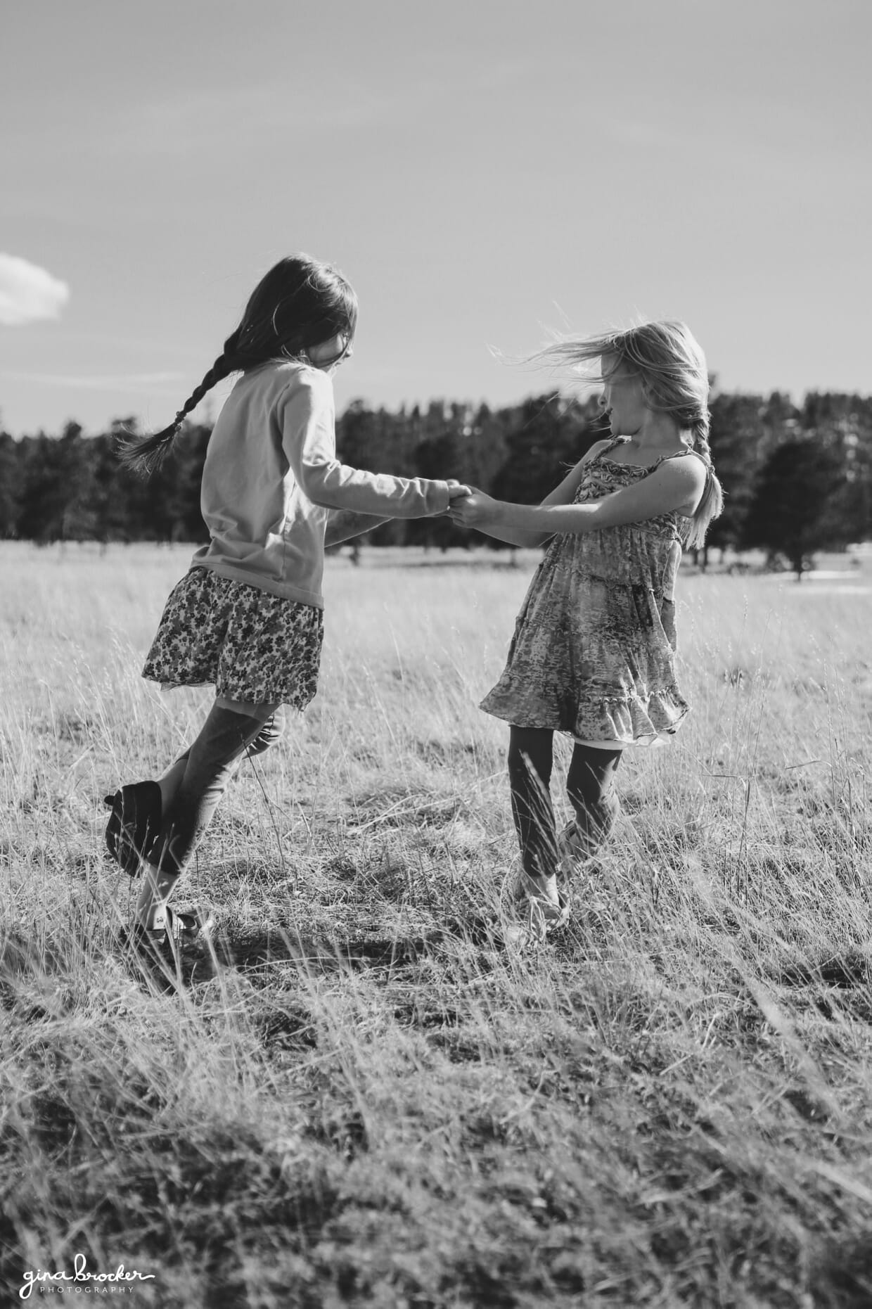 Two sisters spin each other around during their outdoor photo session