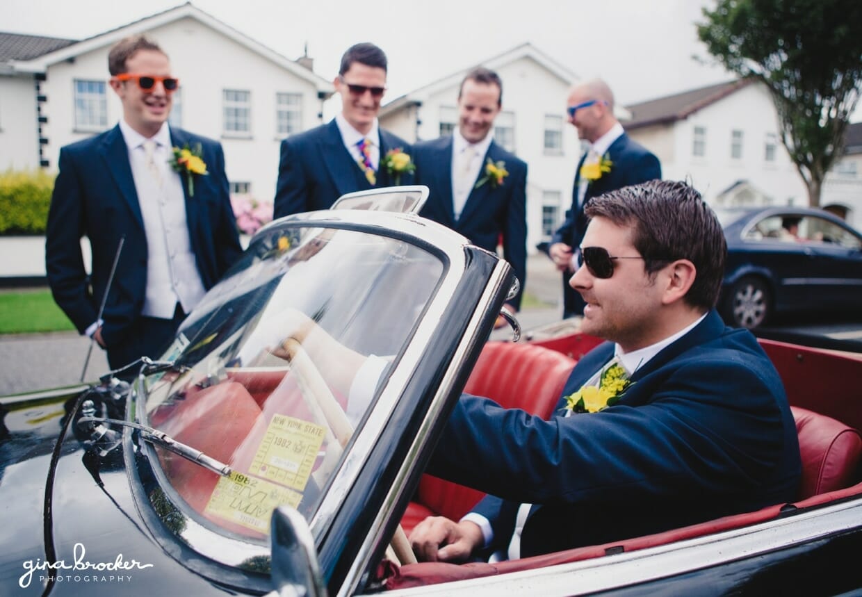 Groomsman drives the groom to the wedding ceremony in a vintage mercedes benz convertible