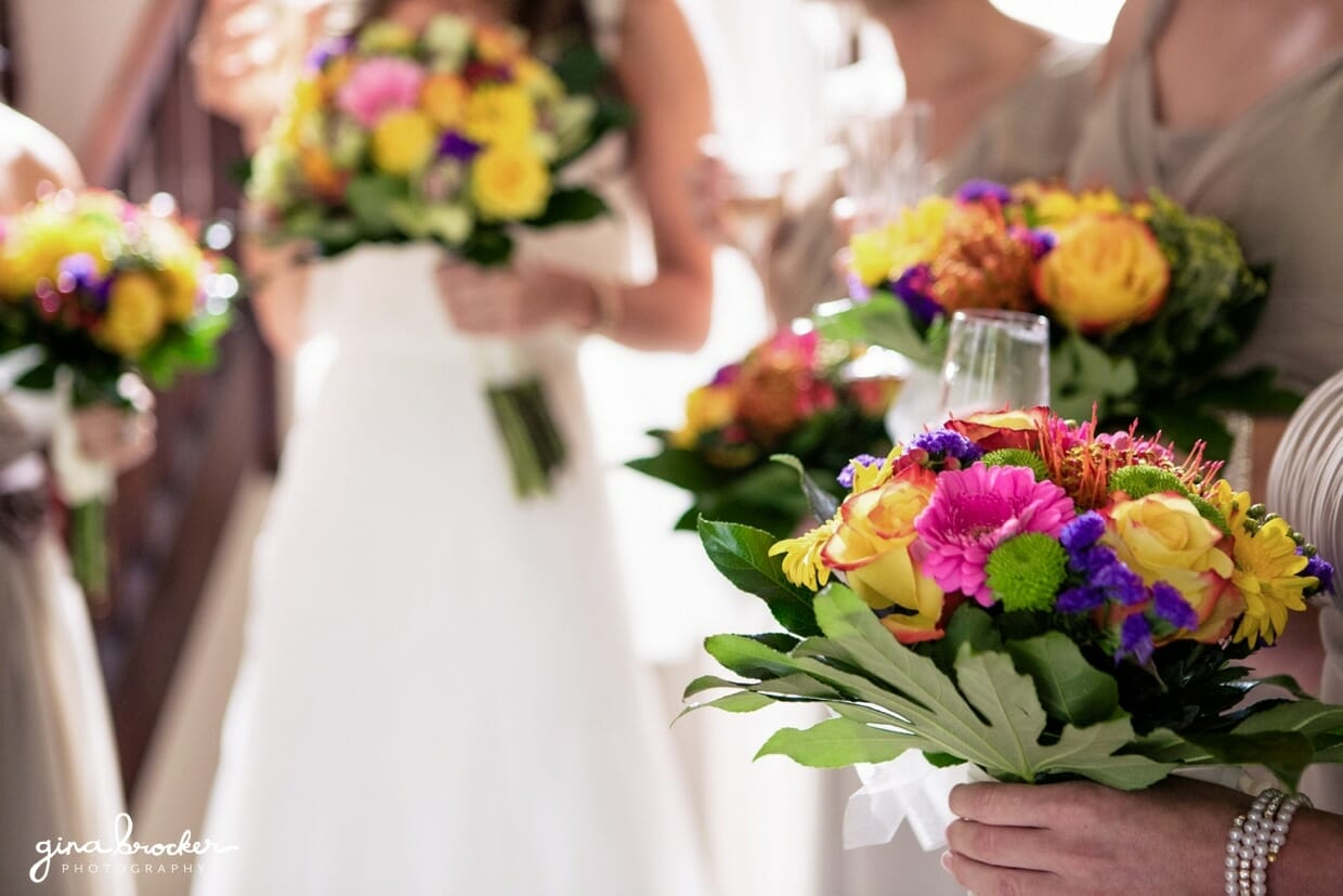 The bride and bridesmaids hold colorful and whimsical bouquets made of daisies, roses and wildflowers