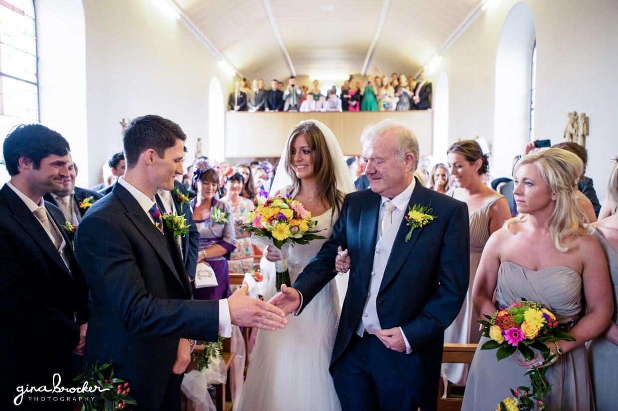 Groom meets bride and her father at the top of aisle during their intimate religious wedding ceremony