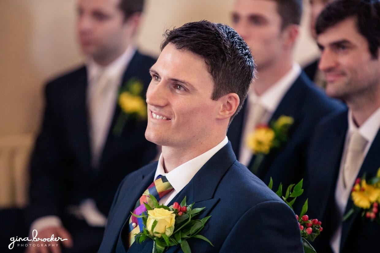 A candid portrait of a groom smiling during his intimate wedding ceremony in a small church