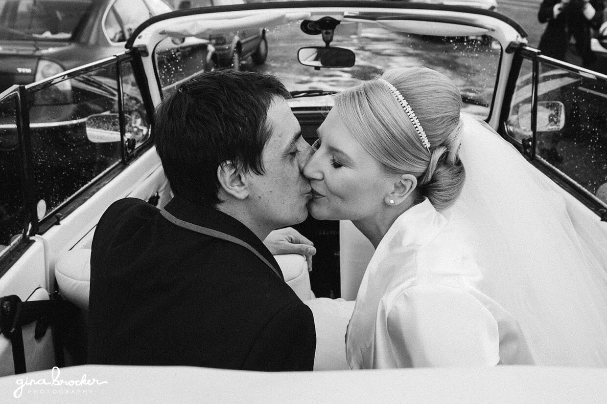 The bride and groom share a kiss in their vintage volkswagen bug after their wedding ceremony