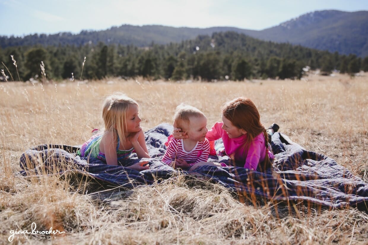 Three girls lay on a blanket and talk during an outdoor kids session