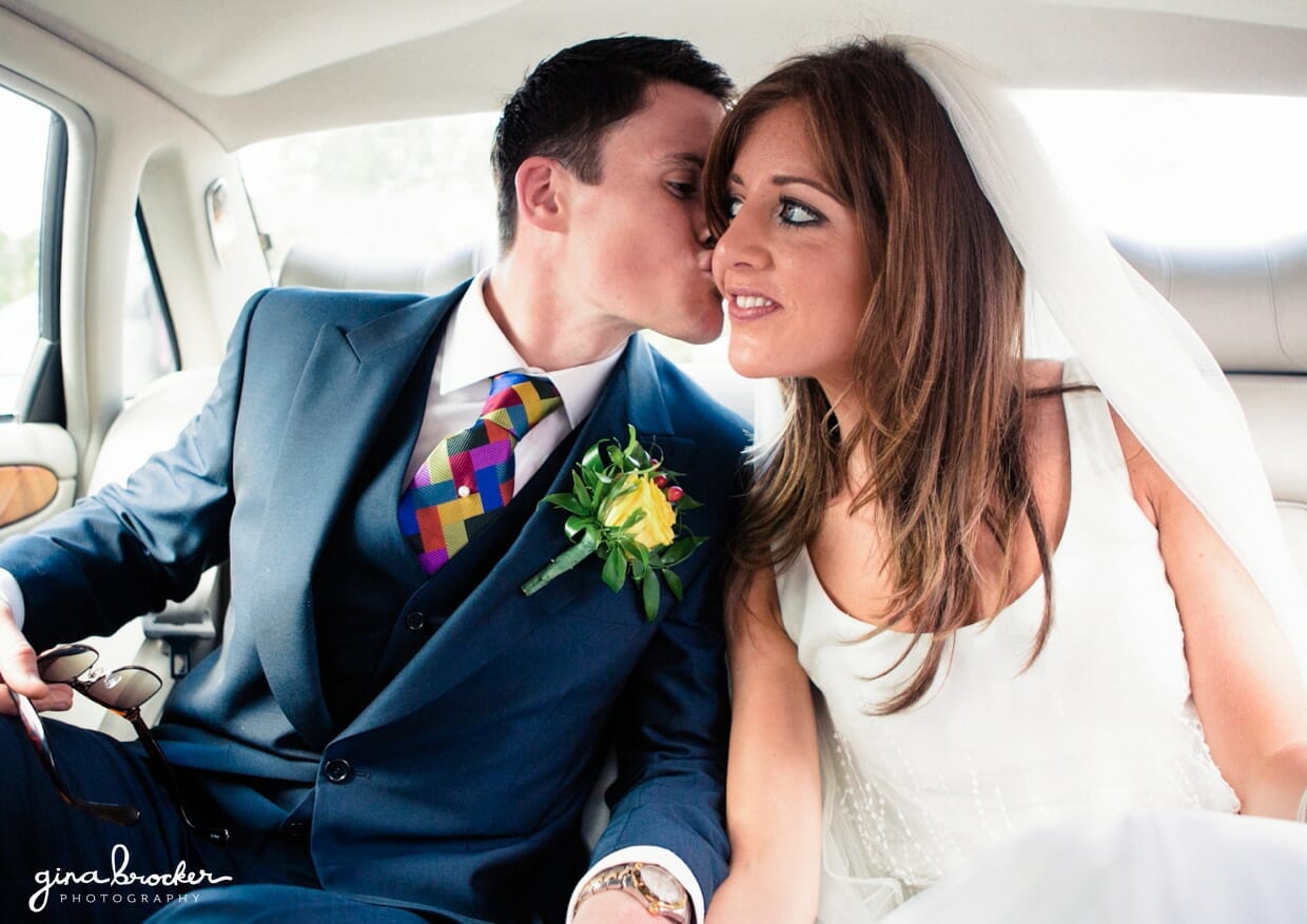 The groom kisses the bride on her cheek as they pull away in their vintage wedding car