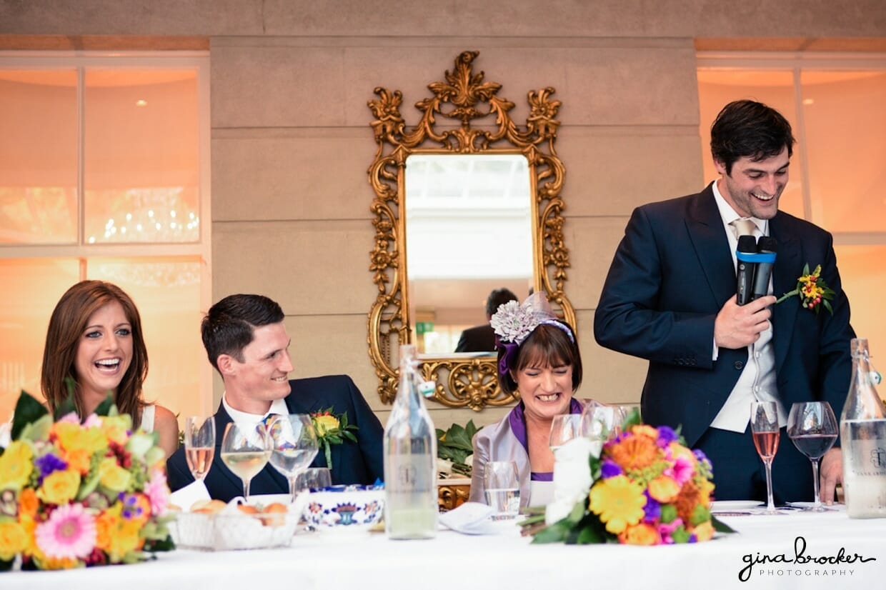 The bride and groom laugh during the best man's hilarious wedding speech