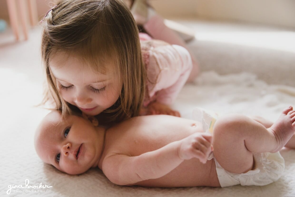 Little girl kissing her baby sister during a family photo session at home