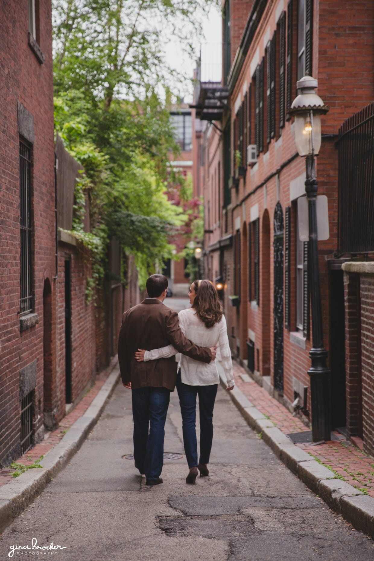 A couple walk arm and arm down the streets of beacon hill during their relaxed boston engagement session