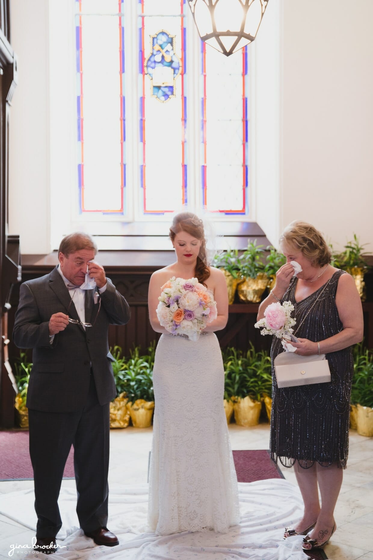 A bride shares a special moment with her parents at the Sacred Heart of Jesus Church, Cambridge, Massachusetts just before she walks up the aisle for her wedding ceremony 