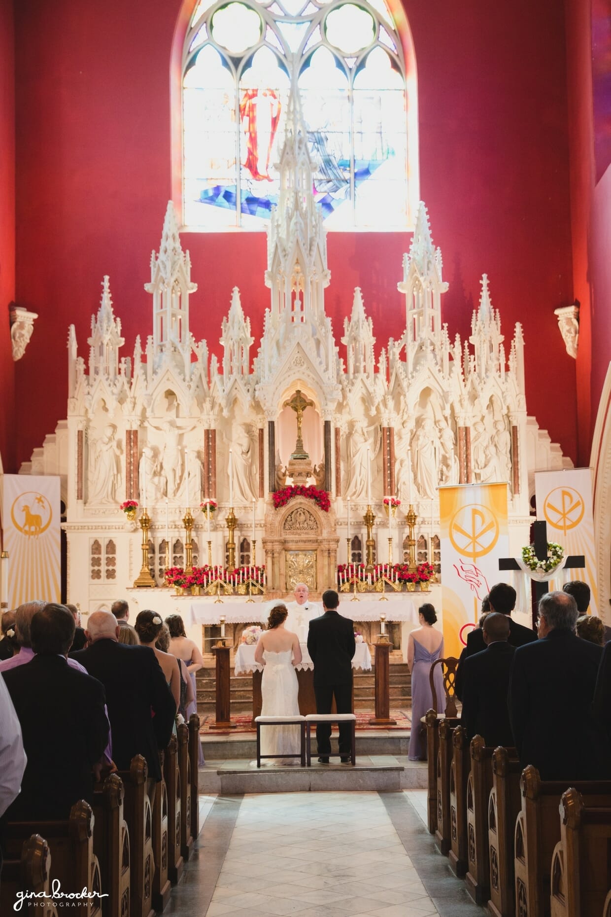 A bride and groom stand at the top of The Sacred Heart of Jesus Church in Cambridge, Massachusetts during their wedding ceremony