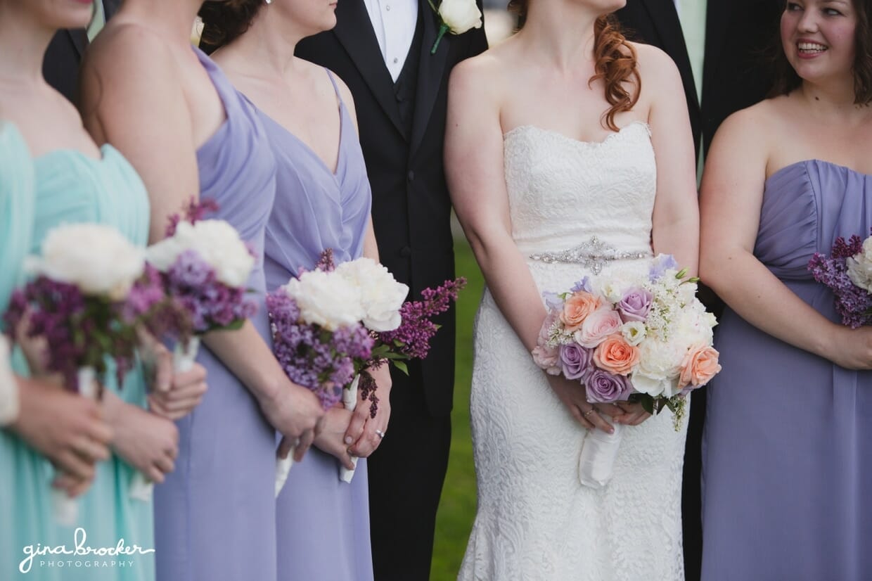 Bridesmaids in aqua and lavender hold simple white and purple bouquets during a wedding in Salem, Massachusetts