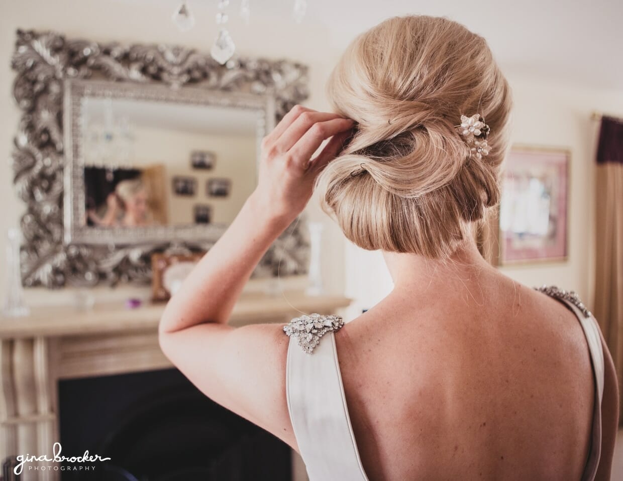 The bride adjust her simple and classic updo on the morning of her garden wedding