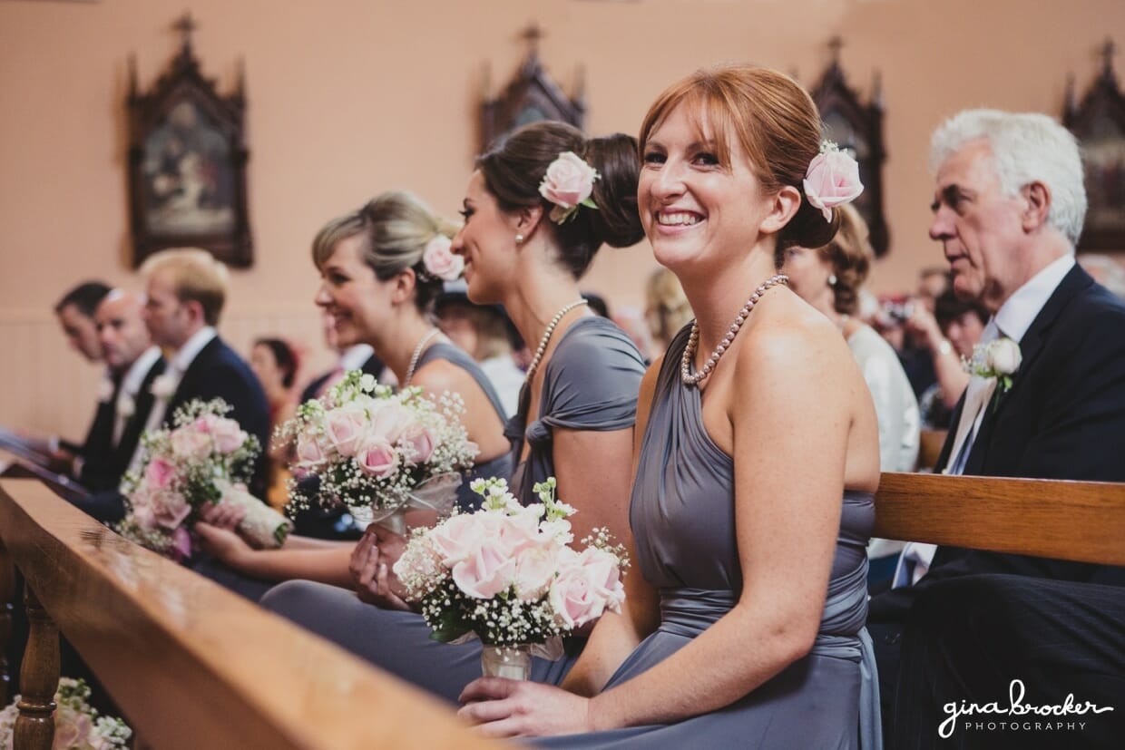 A candid photograph of bridesmaids and wedding guest smiling during a classic wedding ceremony in a church