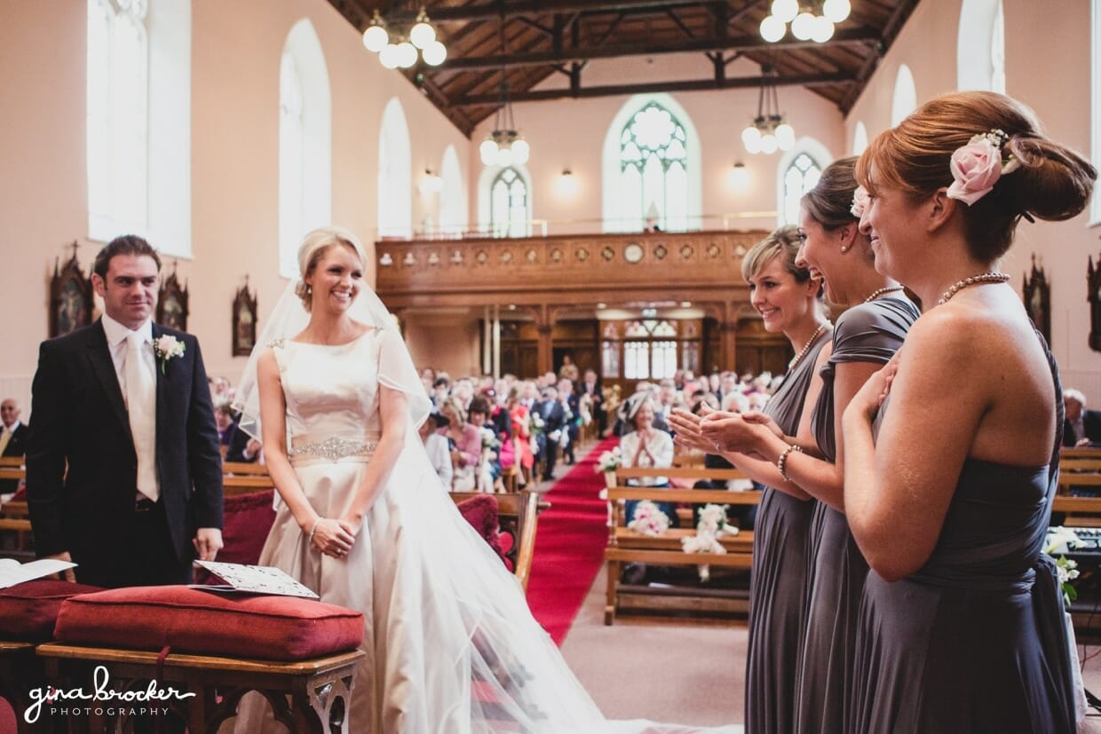 The bridesmaids and guest clap for the bride and groom after saying i do during their religious wedding ceremony