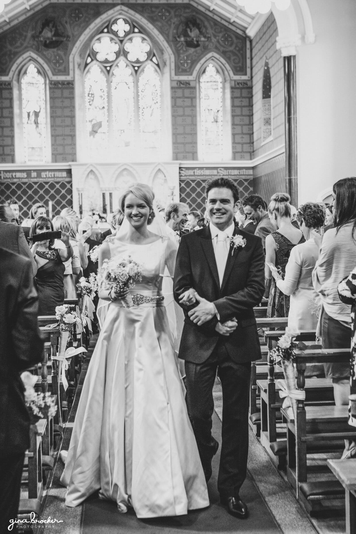 The bride and groom smile as they walk down the aisle after their wedding ceremony in a beautiful church