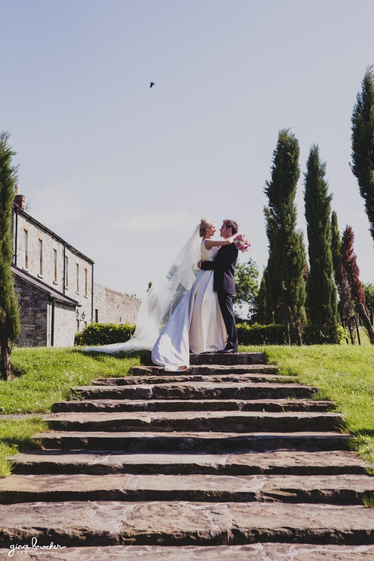 A sweet and natural portrait of a bride and groom at the top of the steps during a classic garden wedding