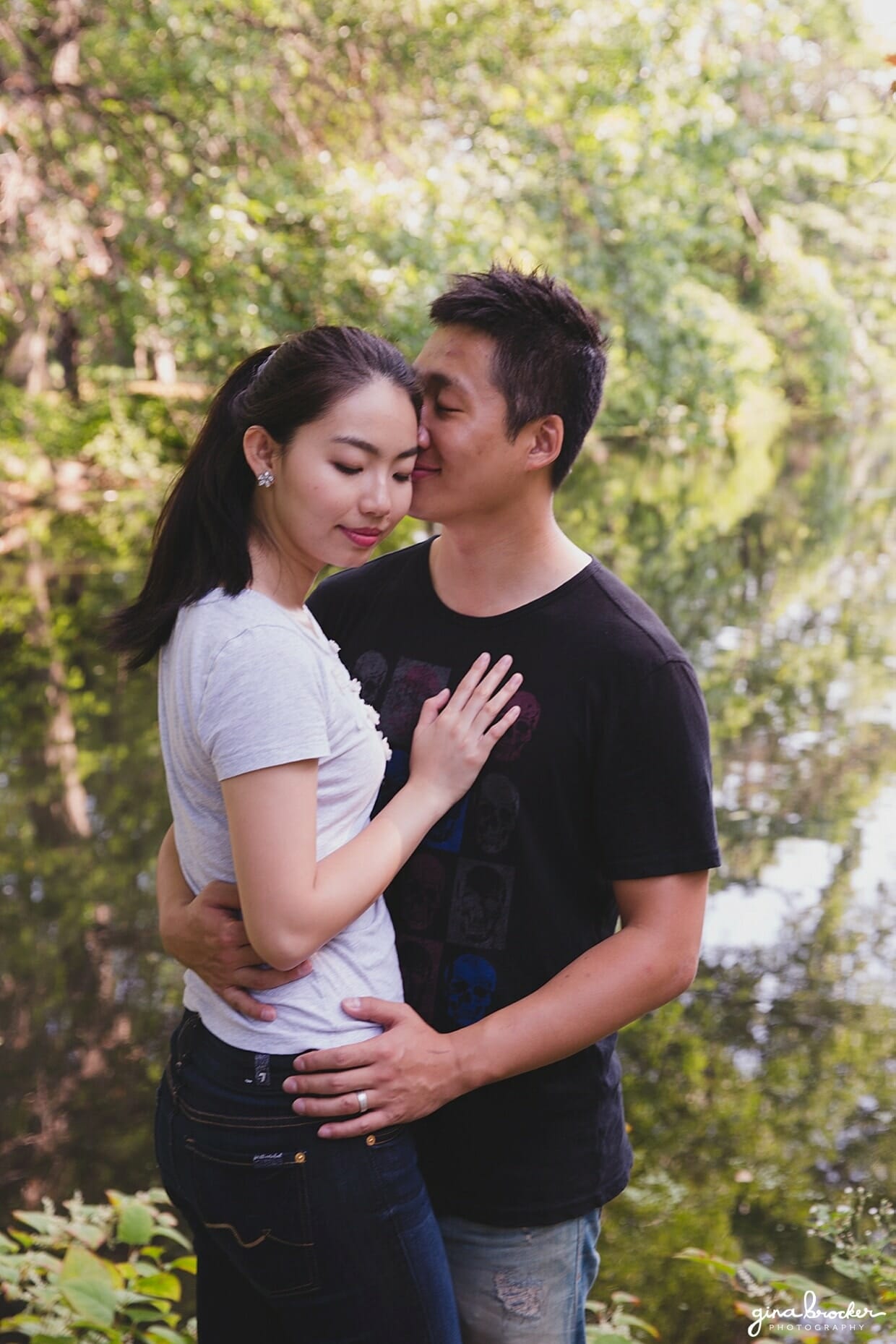 A couple cuddle by the trees during their park engagement session in Boston's back bay fens