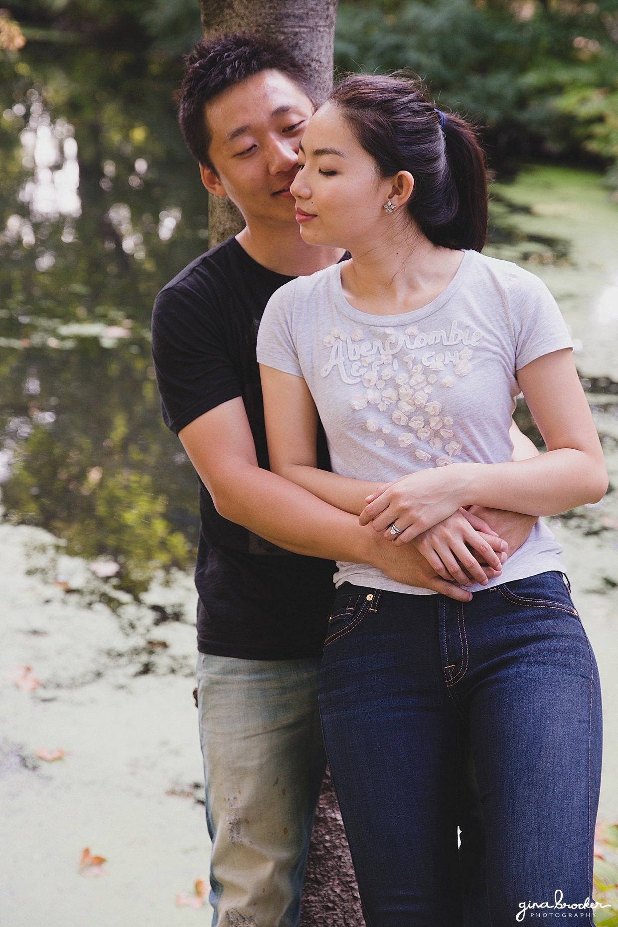 A romantic photograph of a couple cuddling by the water during their park engagement session in back bay fens, Boston, Massachusetts