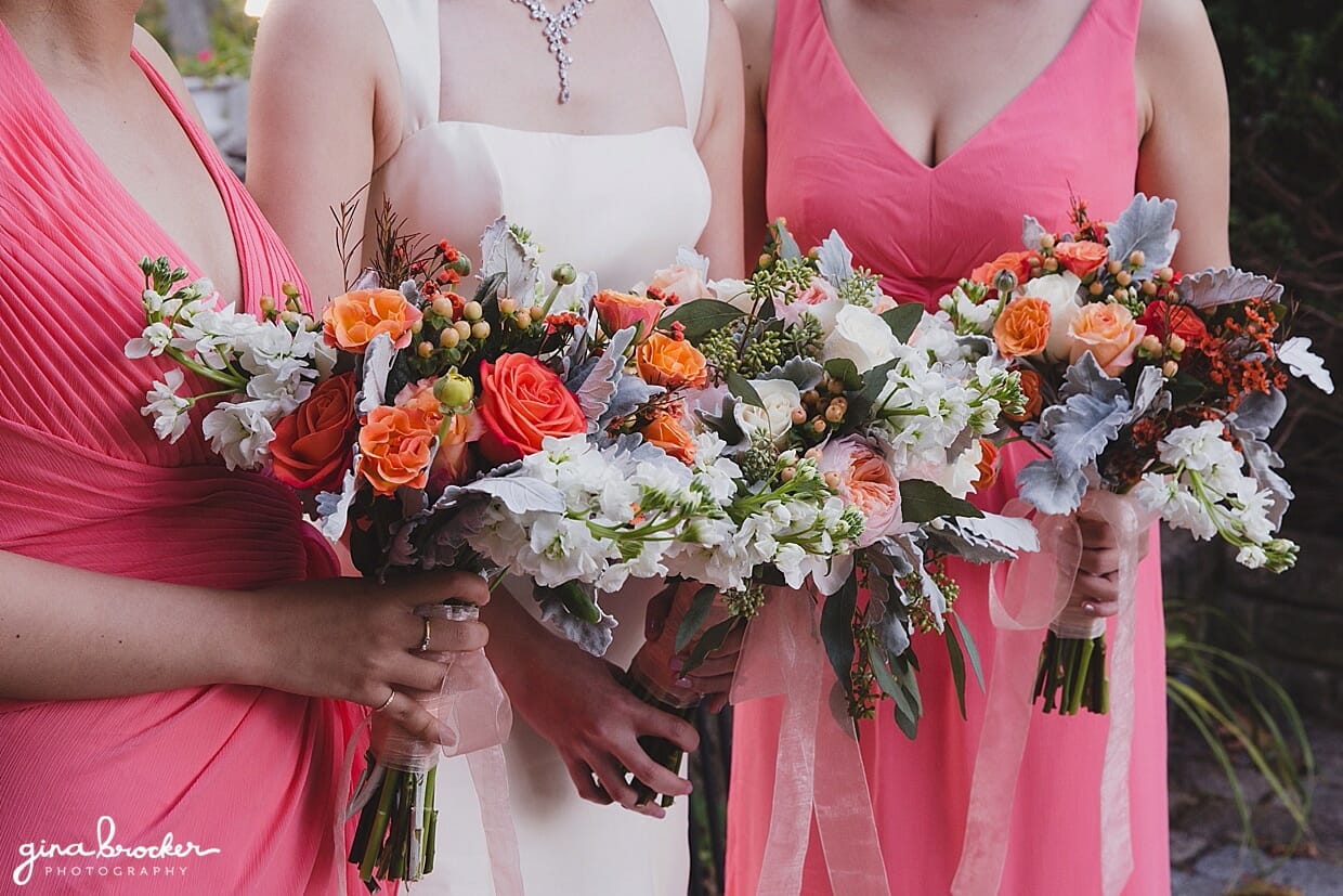The bride and her bridesmaids holding pink, peach and orange wedding bouquets in Hammond Castle