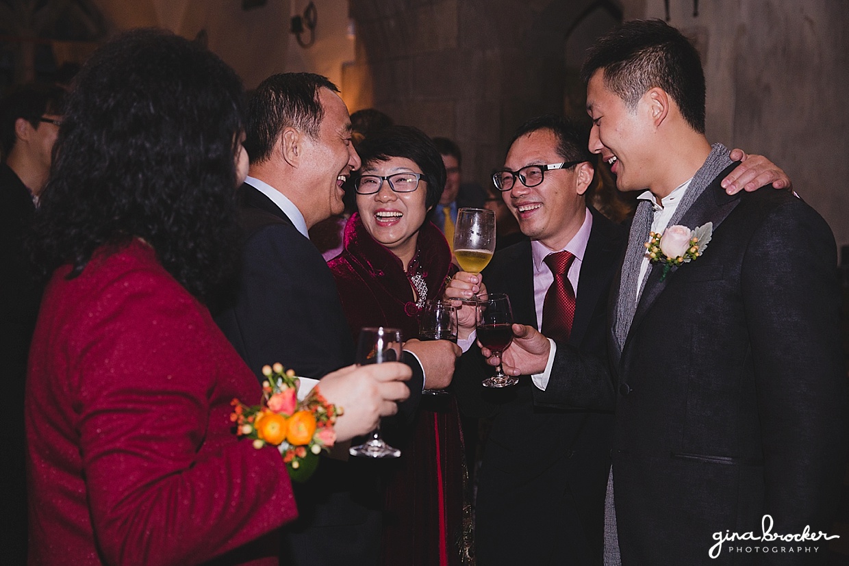 A candid photograph of guests laughing and talking during the cocktail hour of a Hammond Castle Wedding in Gloucester, Massachusetts