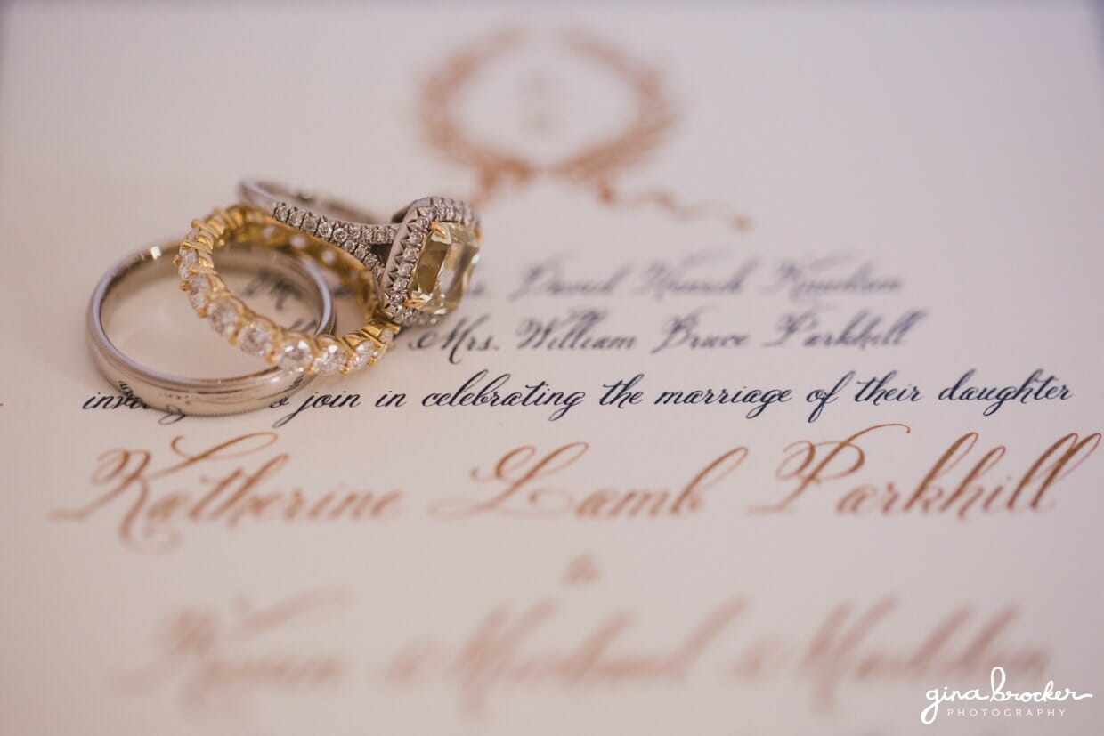 Antique inspired silver and gold wedding rings sit atop a classic wedding invitation for a nantucket wedding