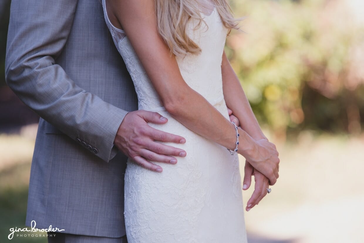 A detailed photograph of a groom holding his bride around the waist during their first look at the Westmoor Club in Nantucket, Massachusetts
