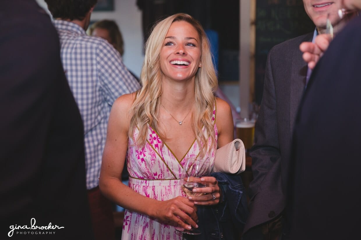 A candid photograph of a woman laughing while she talks with friends at a Nantucket wedding rehearsal dinner in Back Yard BBQ restaurant, Massachusetts