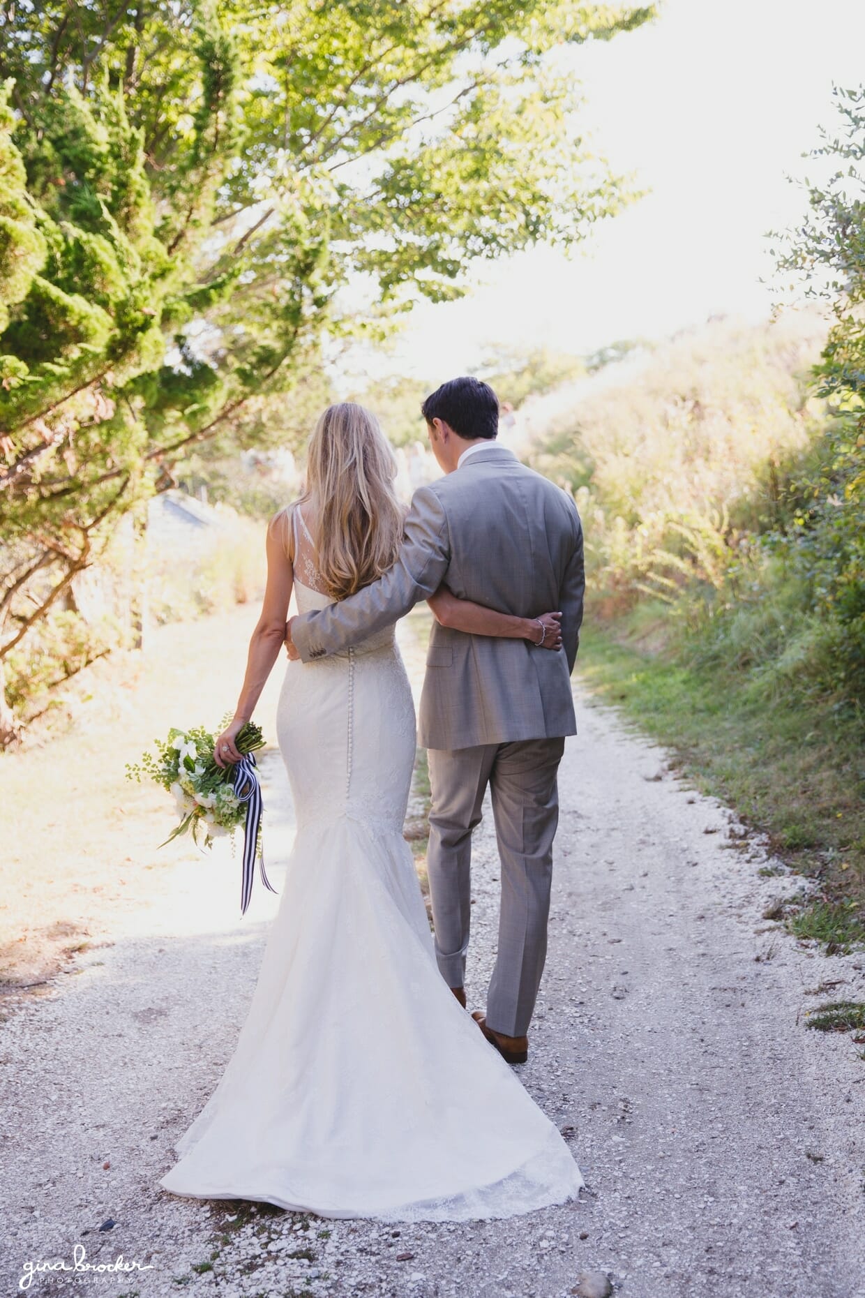 A beautiful and romantic portrait of a bride and groom walking down a path together before their Nantucket wedding at the Westmoor Club