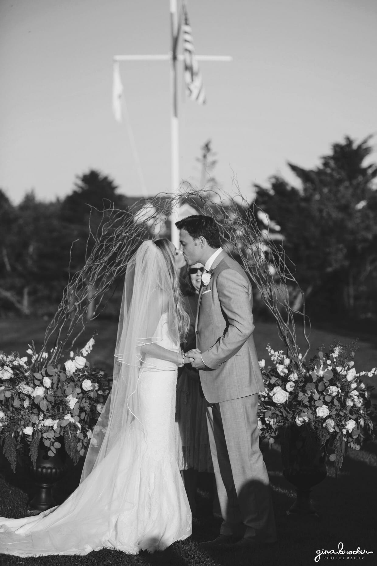 The bride and groom share their first kiss as husband and wife during their sunny outdoor wedding ceremony at the Westmoor Club in Nantucket, Massachusetts