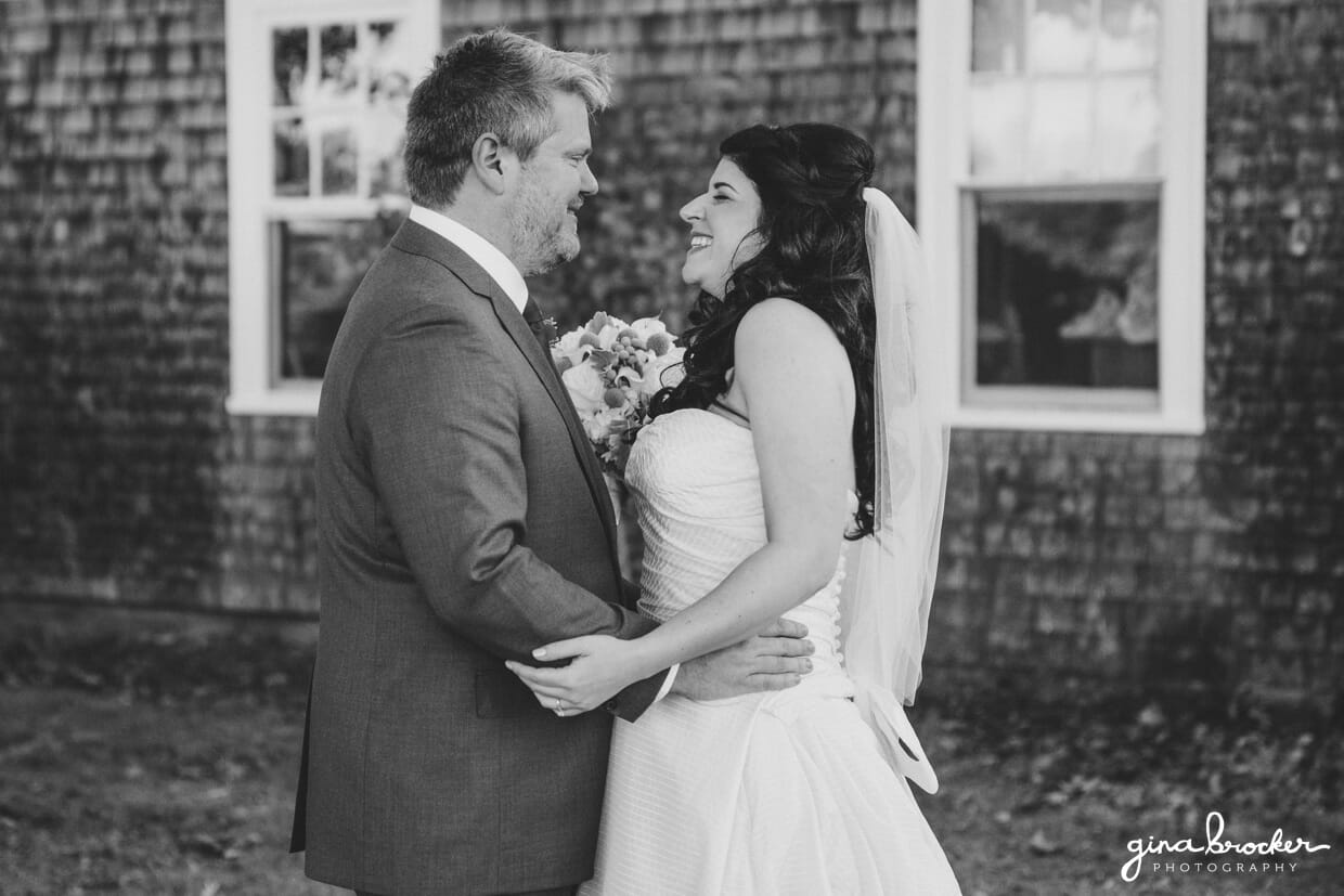 A candid portrait of a bride and groom smiling while they hug each other during the first look of their oxford farm wedding in Massachusetts