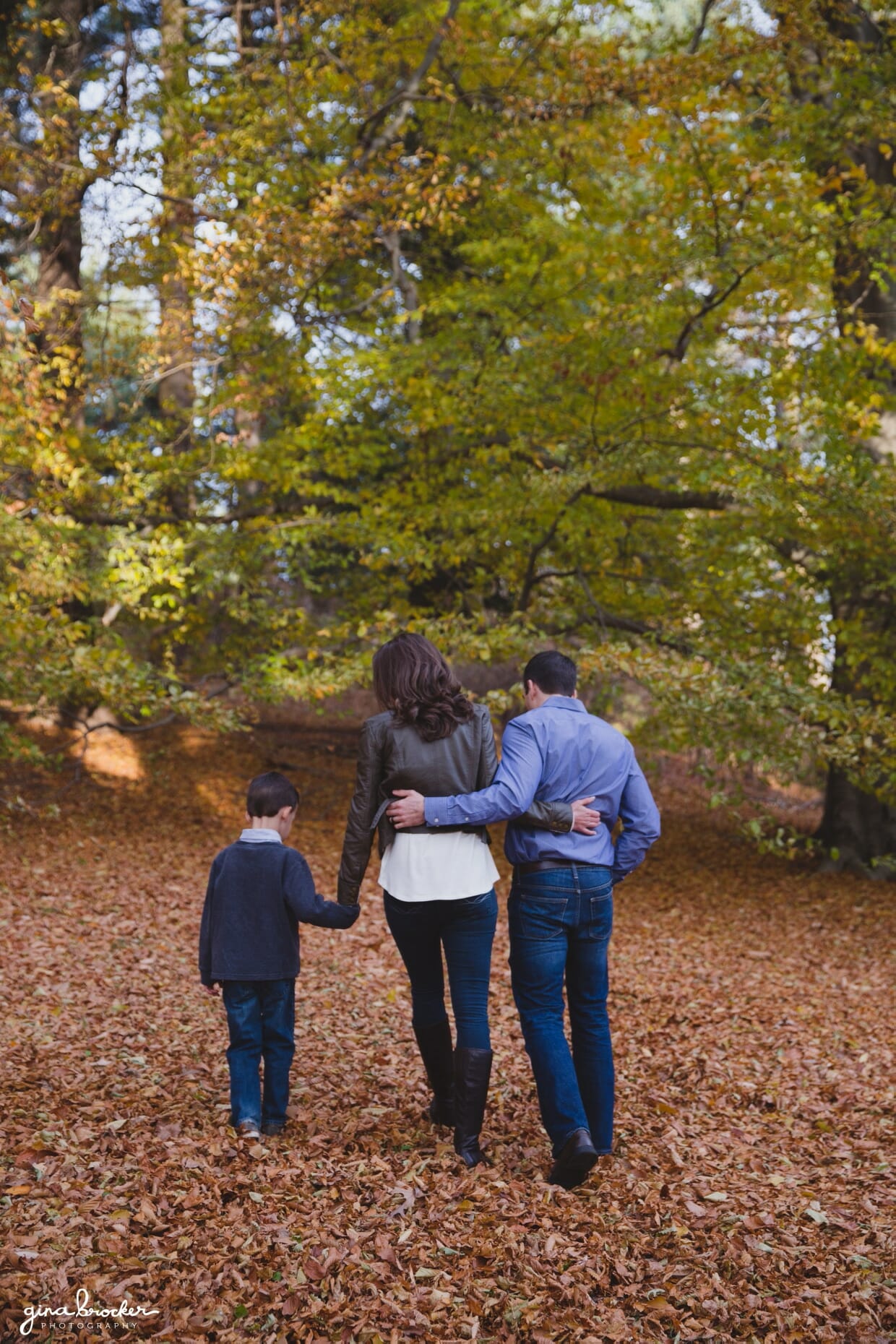 A sweet photograph of family walking together in the woods during their fall family photo session in Boston's Arnold Arboretum