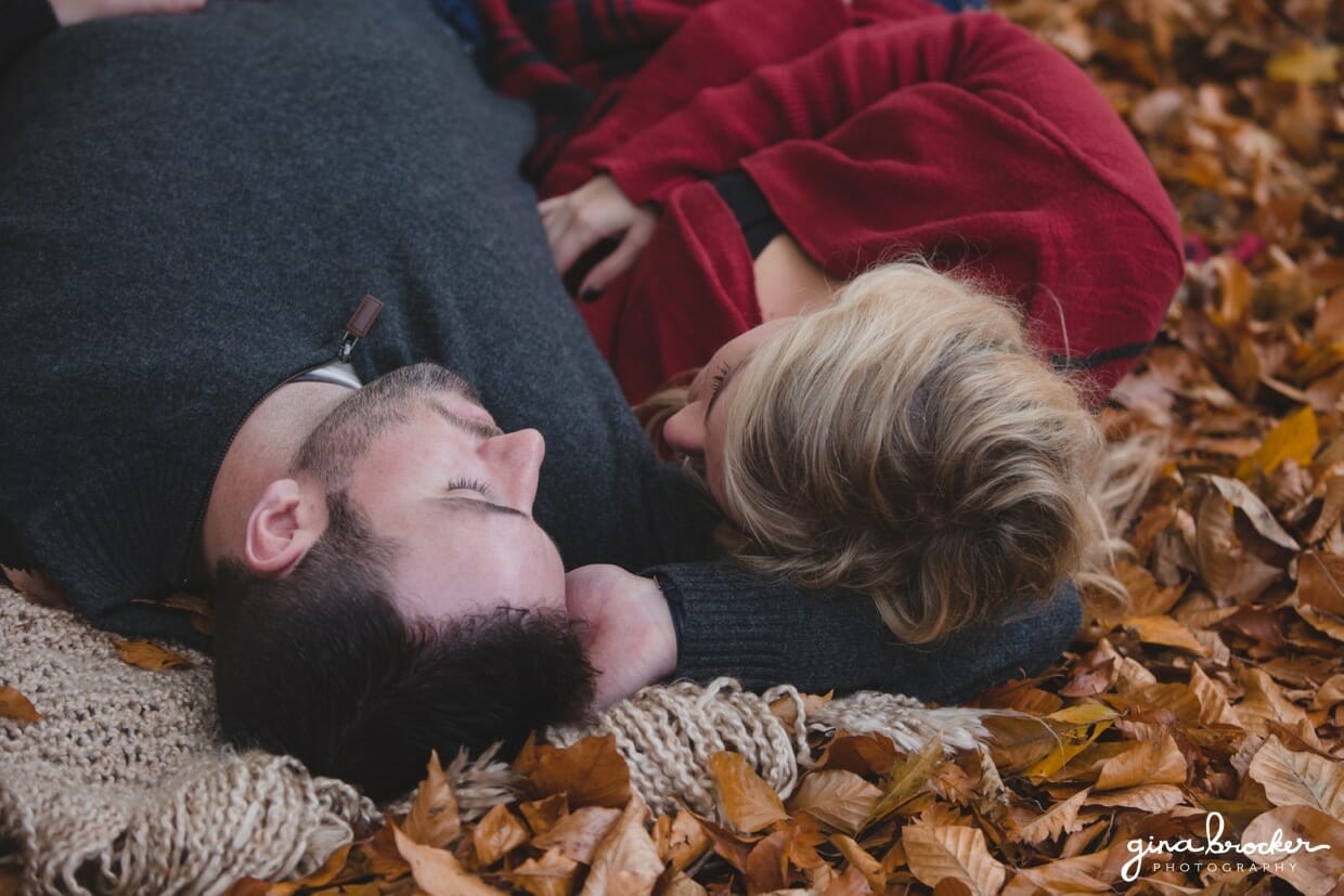 A unique photograph of a couple laying together on a blanket during their fall couple session at the Arnold Arboretum in Boston, Massachusetts