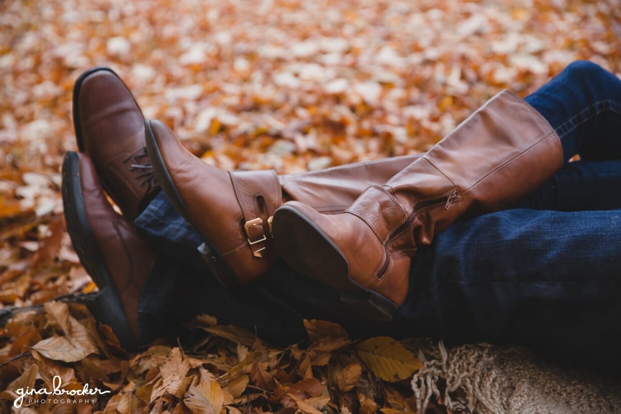 A detailed photograph of a couples boots as they lay together in the fallen leaves during their fall themed couple session at the Arnold Arboretum in Boston, Massachusetts
