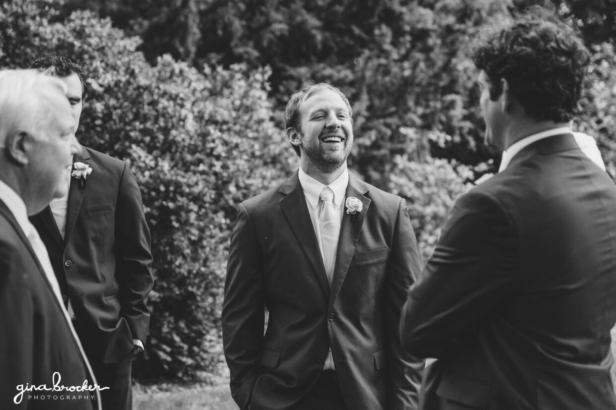 A candid photograph of Groomsmen talking and laughing during a classic and elegant wedding in Boston, Massachusetts