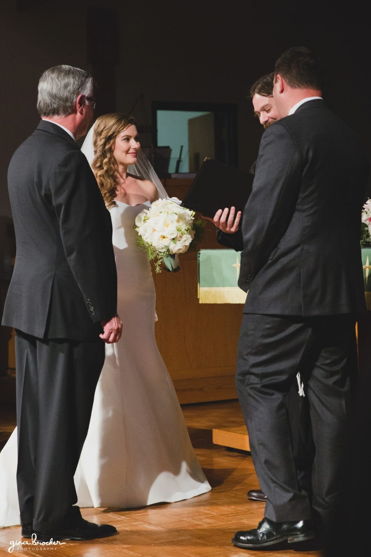 The bride smiles during her church wedding ceremony of her classic and elegant Boston Wedding