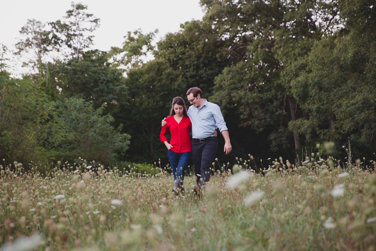 A beautiful and natural photograph of a couple walking in a field at the Arnold Arboretum during their Boston Engagement Session