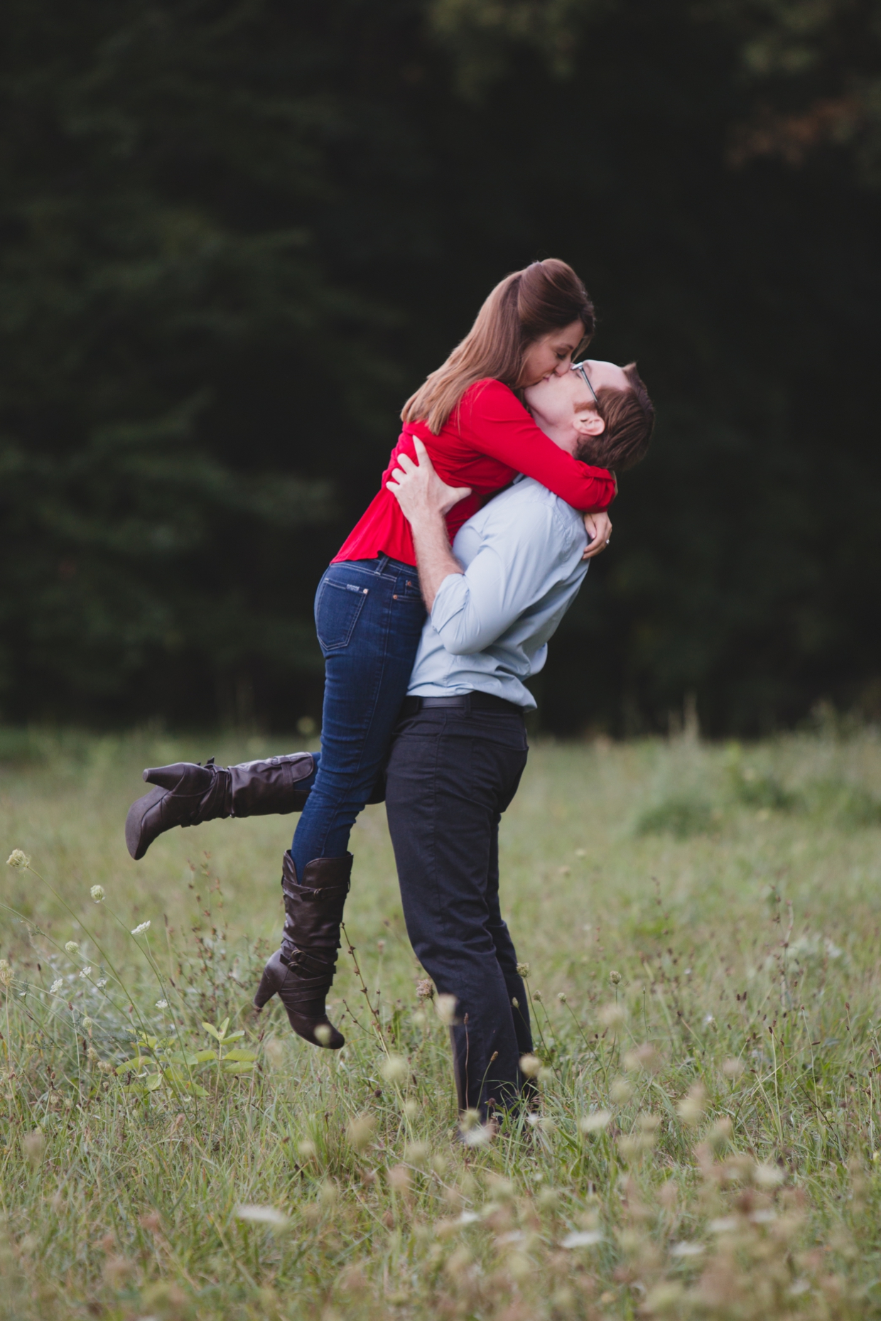 A romantic photograph of a couple kissing in a field during their engagement session at the Arnold Arboretum in Boston, Massachusetts