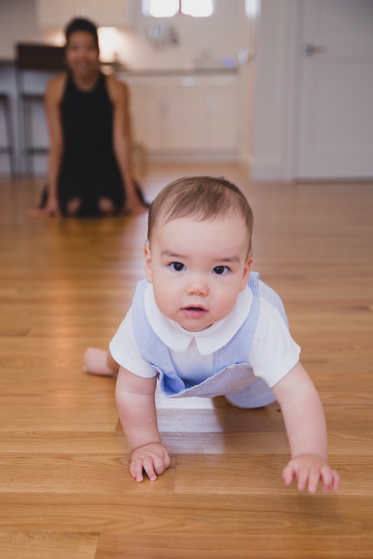 A cute photograph of a baby boy crawling during on his living room floor during an in home family photo session in Jamaica Plain