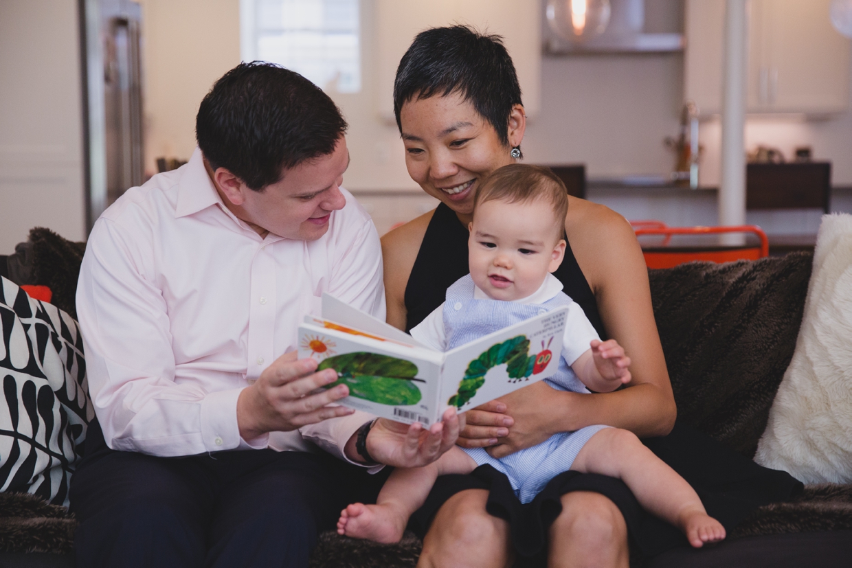 A sweet photograph of parents reading a book to their baby boy in their Jamaica Plain home during a documentary family photo session