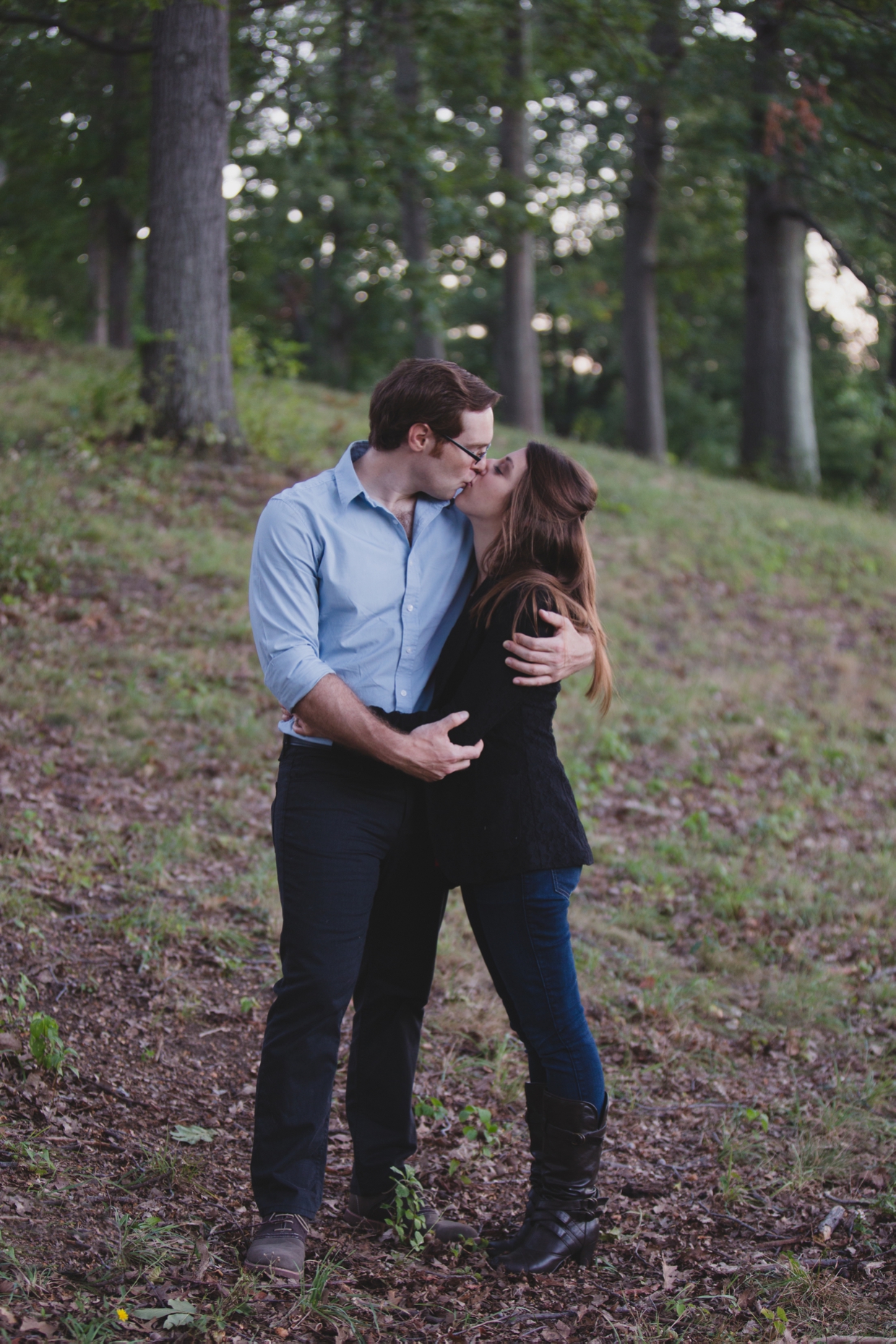 A beautiful photograph of a couple kissing in the forest during their engagement session at the Arnold Arboretum in Boston, Massachusetts