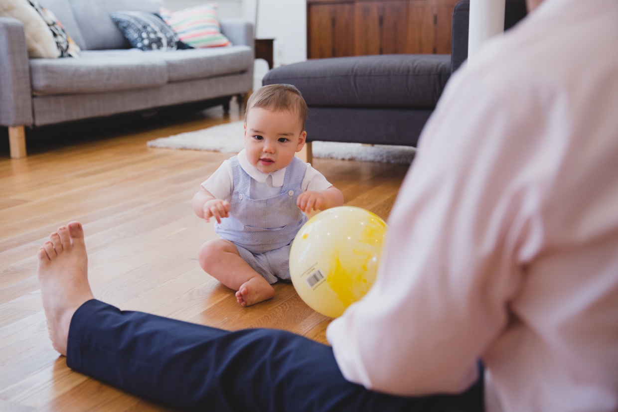 A sweet photograph of baby boy playing on the floor with his dad during an in home family photo session