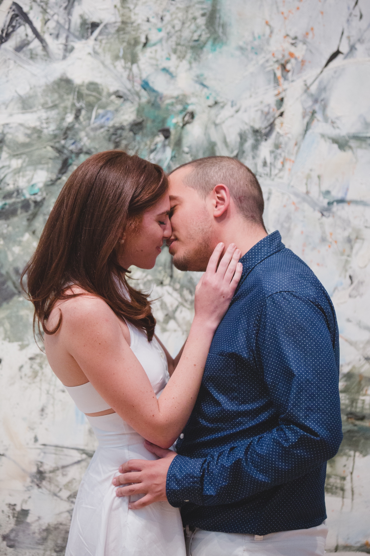 A sweet and romantic photograph of a couple kissing in front of a contemporary painting at the Museum of Fine Arts in Boston