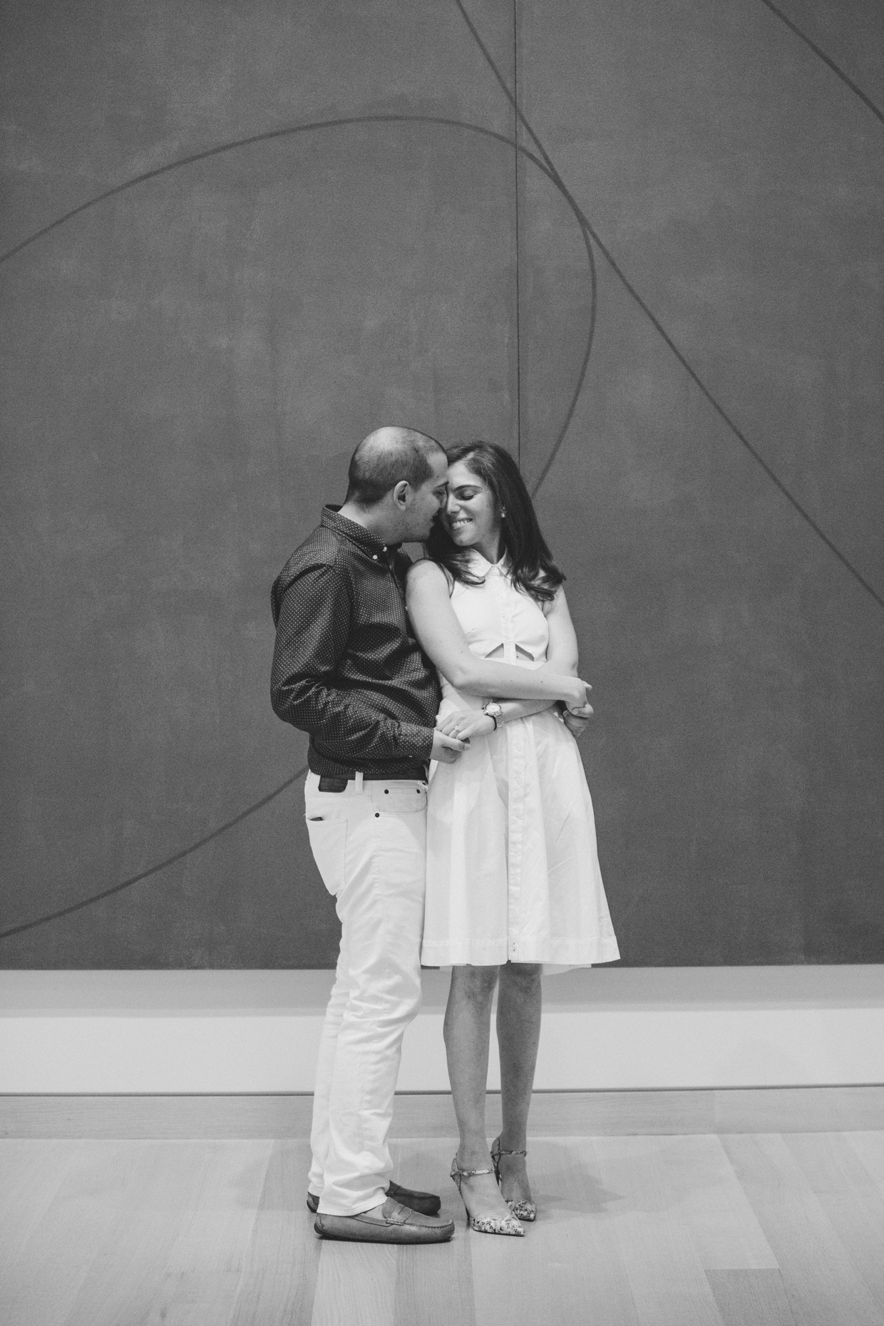 A sweet photograph of a couple hugging in front of a contemporary painting during their engagement session at the Boston Museum of Fine Arts