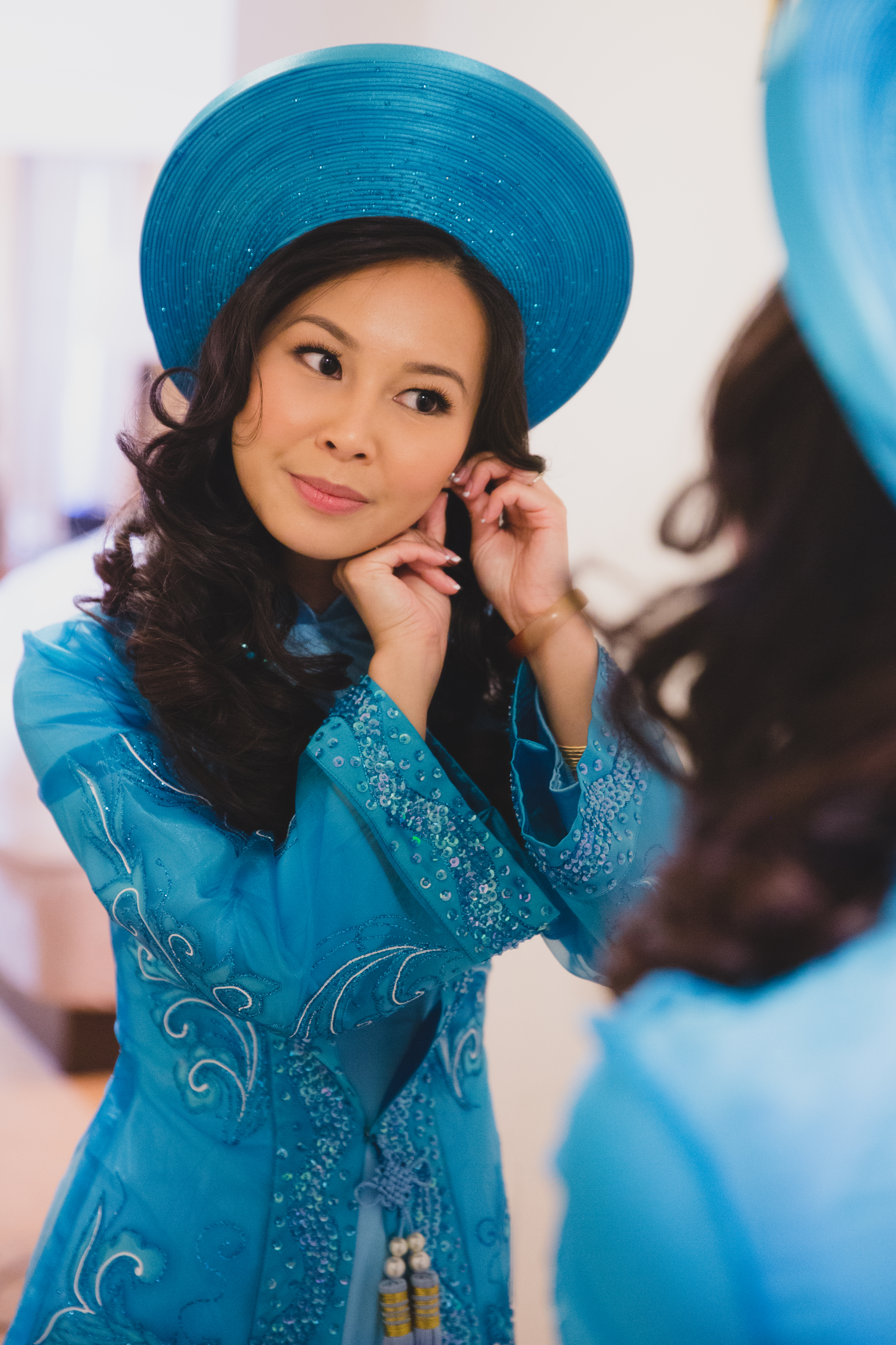 A bride puts on her earrings before leaving for her vietnamese tea ceremony in Boston